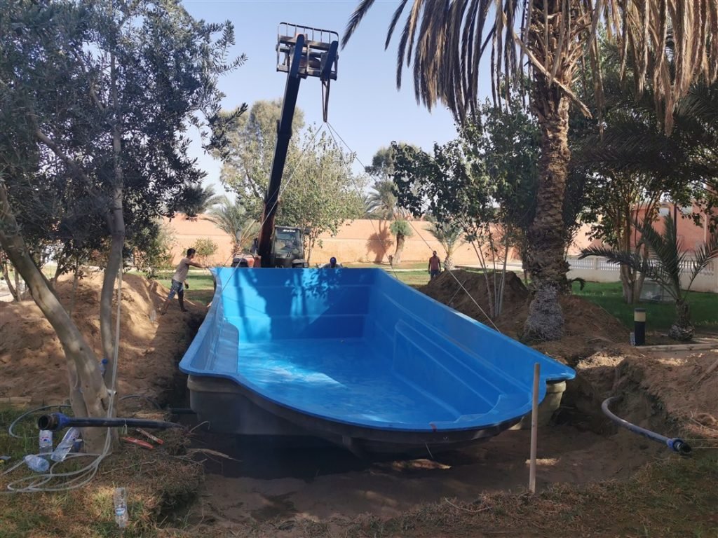 Coque de piscine PRV bleue posée dans sa fouille par un chariot élévateur