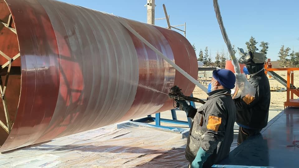 Deux opérateurs projetant la résine et la fibre de verre sur une virole